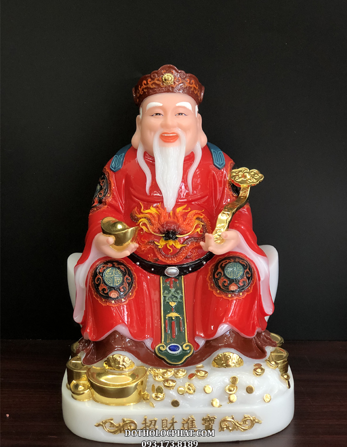 Tượng Thần Tài màu đỏ gấm, được khắc họ với dáng vẻ uy nghiêm tôn quý, tay cầm một thỏi vàng lớn, râu tóc bạc phơ, y phục chỉnh tề